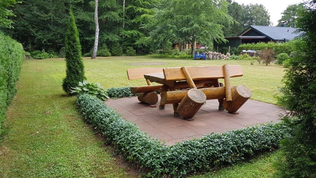 Gartenbereich mit rustikaler Holz-Sitzgruppe auf dem Grundstück des Ferienhauses in Gelbensande – Referenzobjekt 5613 – Büchel Immobilien Rostock